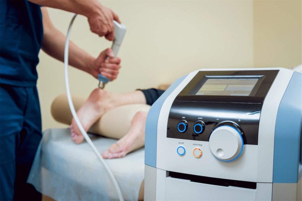 Physiotherapist administering extracorporeal shock wave therapy to a patient to treat heel pain